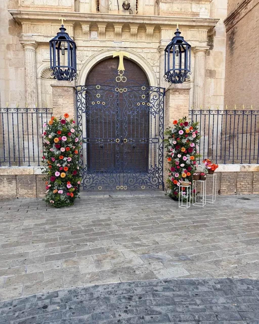 Portón monumental decorado con dos columnas florales de colores vivos para una ceremonia