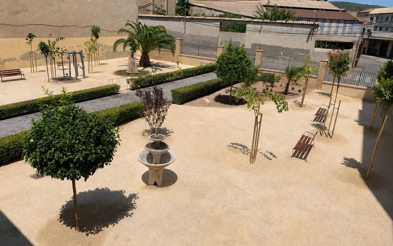 Jardín formal con pavimento de albero, setos recortados, arbolado joven y fuente central