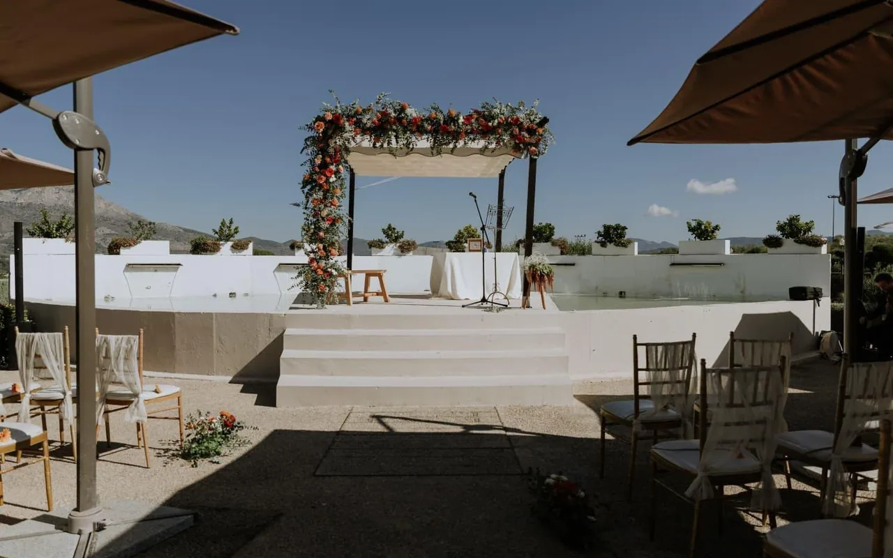 Pérgola de ceremonia decorada con flores, con las montañas al fondo